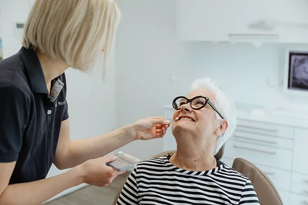 Am Mund der Patientin wird eine Verlendschale gehalten, um den Farbton zu ermitteln
